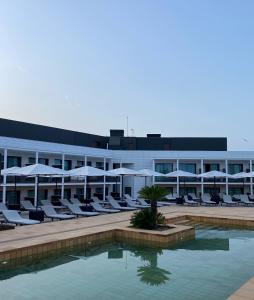 普拉加德阿罗Silken Platja d'Aro的一个带游泳池、椅子和遮阳伞的酒店