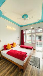 麦罗肯机Mitra Hostel Mcleodganj的一间卧室配有两张带红色和黄色枕头的床