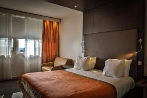 尼姆瓦岱勒酒店和Spa的配有一张床和一把椅子的酒店客房