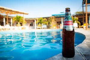 曼克拉Mancora y Sol的游泳池旁的一瓶啤酒