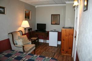 惠灵顿Hadovka Lakeside Inn的配有床、电视和椅子的房间