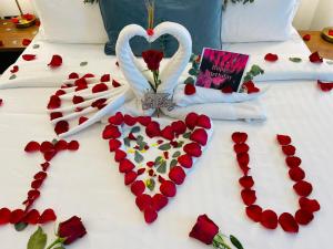 多哈Cielo Hotel Lusail Qatar的一张床上有两只天鹅和红玫瑰