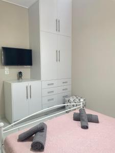 爱琴娜岛Aiginetan Apartments的一间卧室配有一张带电视和白色橱柜的床。