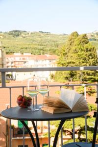 迪亚诺马里纳Hotel & Apartments Sasso的一张桌子,上面放着两杯葡萄酒和一本书