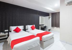 怡保Hotel Pulai Ipoh的两张位于酒店客房的床铺,配有红色枕头