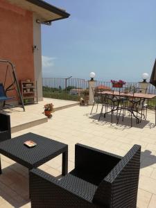 米罗Villa Etna Masi'的一个带桌椅的庭院,背景为大海