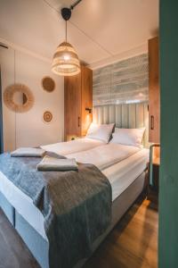 里沃RResort - nowe KLIMATYZOWANE domki z PODGRZEWANYM Basenem, Sauna, WiFi, parking w cenie!的一间卧室配有一张大床和一个吊灯。