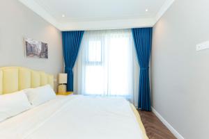 归仁Altara Apartment Quy Nhon的一间卧室配有一张带蓝色窗帘的大床
