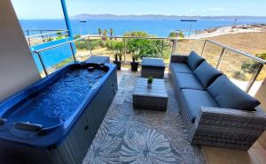 拉夫里翁PORTO D'ORO LUXURY APARTMENT的带沙发的阳台上的大型蓝色热水浴池