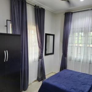 Ekehen247 City Apartment - Home away from home的一间卧室配有紫色窗帘、一张床和一个窗户
