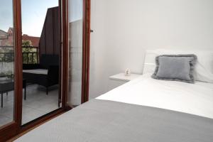 拉巴克Apartment Nia的一间带白色床的卧室和一个阳台