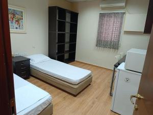 内坦亚Coral guest house Netanya的小房间设有两张床和一台冰箱