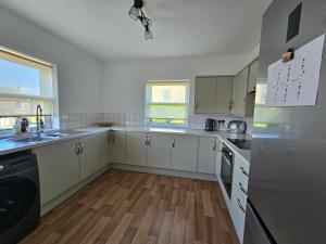 RavensworthRavensworth Cottage的厨房铺有木地板,配有白色橱柜。