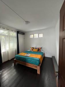 马埃堡Le Manguier的一间卧室配有一张带绿色和橙色毯子的床