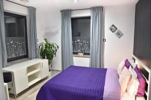 赫维兹Water Lily Boutique B&B and Bungalow的一间卧室设有紫色的床和窗户