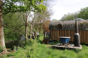 卡纳芬Caban Delor. Off-grid glamping experience. Walking distance into Caernarfon. 20-min drive to Snowdonia or Anglesey.的浴缸位于rv旁边的木制平台上