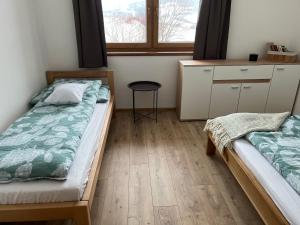 Vyšný KubínChata Pod Skalkami的一间卧室设有两张床、一张桌子和一个窗口