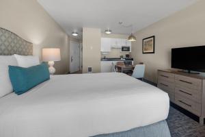 林肯市鹈鹕海岸酒店的卧室配有一张白色大床和一台平面电视。