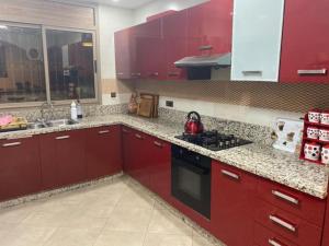 Ait Melloulأكادير ايت ملول的厨房配有红色橱柜和黑炉