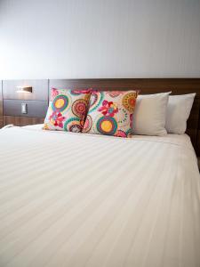 利马Hotel Britania Crystal Collection的一张带白色床单和彩色枕头的床