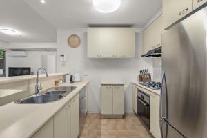 墨尔本Exclusive Stays - Southbank Tower的厨房配有白色橱柜和不锈钢冰箱