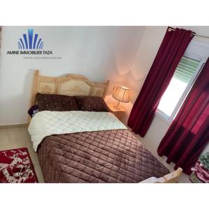 塔扎APPARTEMENT AL WAHDA的一间卧室配有床和红色窗帘的窗户