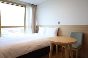 西归浦市Kenny Stay Jeju Seogwipo的一间卧室配有一张床、一张桌子和一个窗户。