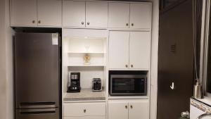 蒙特雷La Finca的厨房配有白色橱柜和黑色冰箱。