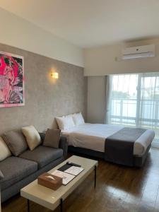 那霸New Normal Hotel in NAMINOUE ニューノーマルホテルイン波の上的酒店客房,配有床和沙发