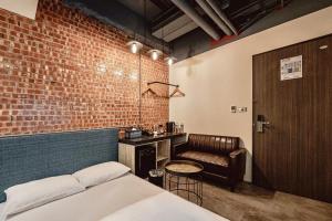 嘉义市嘉义轻行旅的卧室设有砖墙、一张床和一把椅子