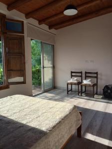 查克拉斯德科里亚Chacras casa Armonia的一间卧室配有一张床、两把椅子和窗户