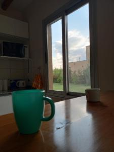 查克拉斯德科里亚Chacras casa Armonia的坐在窗前桌子上的绿咖啡杯