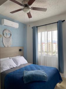普拉亚卡门Departamento en Riviera Maya的一间卧室配有蓝色的床和吊扇