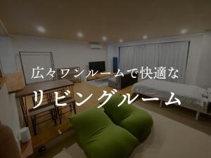 五岛Apartment Goto アパートメント五島的客厅配有绿色沙发和床。