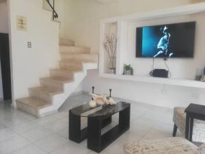 坎昆Casa de Cielo y Mar en Cancún的客厅配有桌子,墙上配有电视