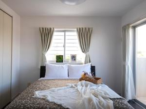 宜野座Dolcevita的卧室配有带白色枕头的床和窗户。