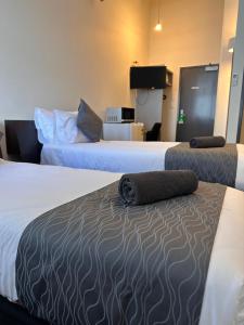 奥克兰Gamma Hotel的两张位于酒店客房的床,配有两张床垫