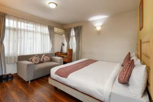 帕坦Shaligram Hotel & Spa的一间卧室配有一张床和一个沙发