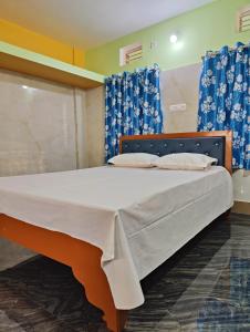 普里Jagannatha Guest House的一张大床,位于带蓝色窗帘的房间