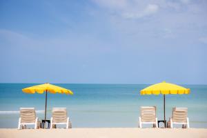 茶云莱海滩The Fair House Beach Resort & Hotel的海滩上的一组椅子和遮阳伞