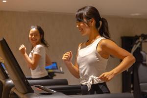 京都THE BLOSSOM KYOTO的两名妇女在健身房跑步机上骑