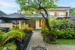 勒吉安Liliy Guest House Kuta - Badung的房屋前设有带椅子和遮阳伞的花园