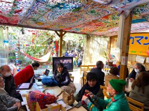 大阪Kamagasaki University of the Arts Cafe Garden Guest House aka Cocoroom的一群人坐在一个房间里桌子旁