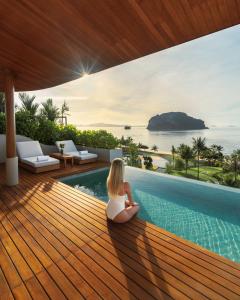 瑶亚岛Anantara Koh Yao Yai Resort & Villas的坐在游泳池旁甲板上的女人