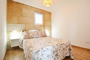 庞特维德拉Casa con jardín en Pontevedra的一间卧室设有一张床和石墙