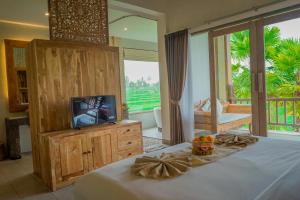 德格拉朗The Nenggala Suite的一间卧室设有一张带电视的床和一个阳台。