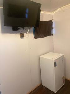 皮雷诺波利斯Salamandra trailerhome的小冰箱旁墙上的电视