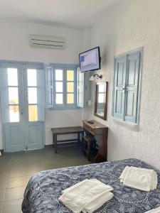 伊亚Panorama Oia Apartments的卧室配有一张床、一张书桌和窗户。