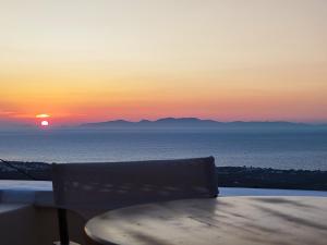 伊亚Panorama Oia Apartments的海洋上的日落,配有一张桌子和一把椅子