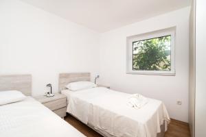 扎博里克Rimagis Apartments的一间白色卧室,配有两张床和窗户